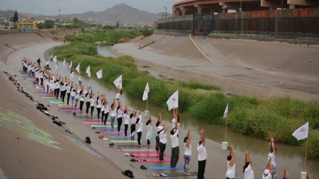 Clase masiva de yoga junto al río Bravo para derribar muros