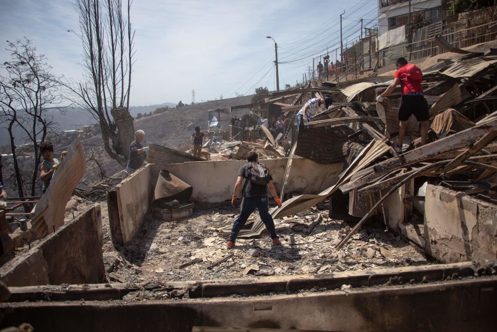 TOPSHOT - Locals search for personal belongings after a forest fire at the Rocuant hill in Valparaiso, Chile, on December 25, 2019. - Around 200 houses were affected by a forest fire Tuesday in Valparaiso, where a red alert was declared. (Photo by Pablo ROJAS MARIADAGA / AFP) (Photo by PABLO ROJAS MARIADAGA/AFP via Getty Images)