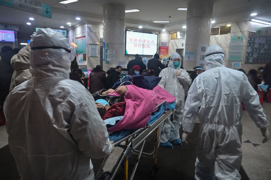 TOPSHOT - In this photo taken on January 25, 2020, medical staff wearing protective clothing to protect against a previously unknown coronavirus arrive with a patient at the Wuhan Red Cross Hospital in Wuhan. - The number of confirmed deaths from a viral outbreak in China has risen to 54, with authorities in hard-hit Hubei province on January 26 reporting 13 more fatalities and 323 new cases. (Photo by Hector RETAMAL / AFP) (Photo by HECTOR RETAMAL/AFP via Getty Images)