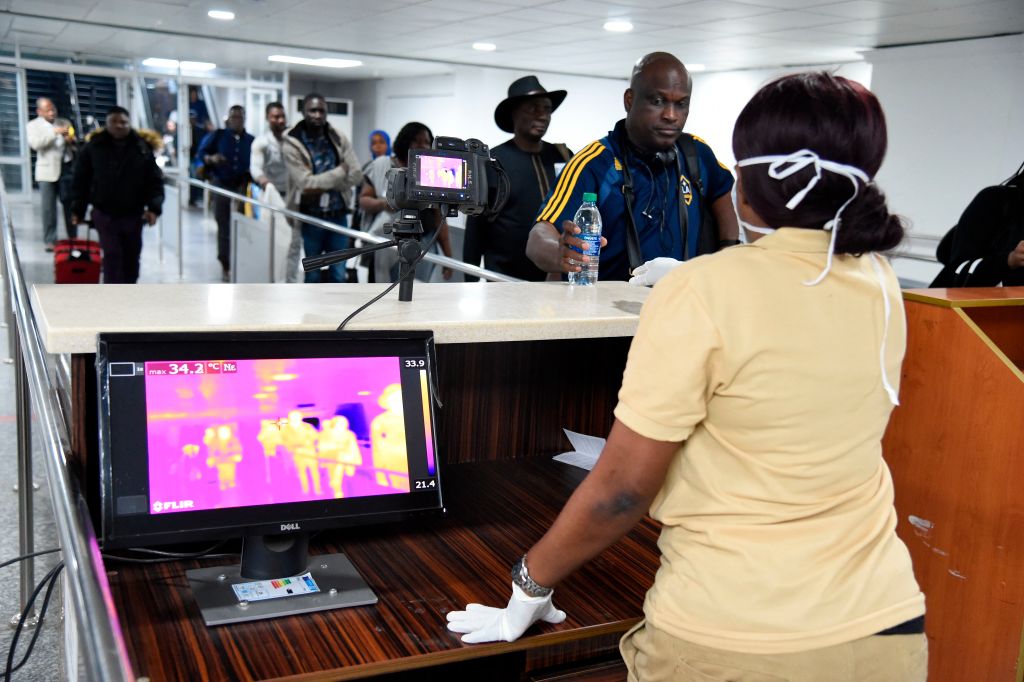 TOPSHOT - A Port Health Service staff member stands next to a thermal scanner as passengers arrive at the Murtala Mohammed International Airport in Lagos, Nigeria, on January 27, 2019. - The Port Health Services Unit of the Federal Ministry of Health in Nigeria has been placed on alert and has heightened screening measures at the points of entry to screen travellers arriving the country. The Nigeria Immigration Service and Port Health Services have expressed fears over the outbreak of Coronavirus in China. (Photo by PIUS UTOMI EKPEI / AFP) (Photo by PIUS UTOMI EKPEI/AFP via Getty Images)