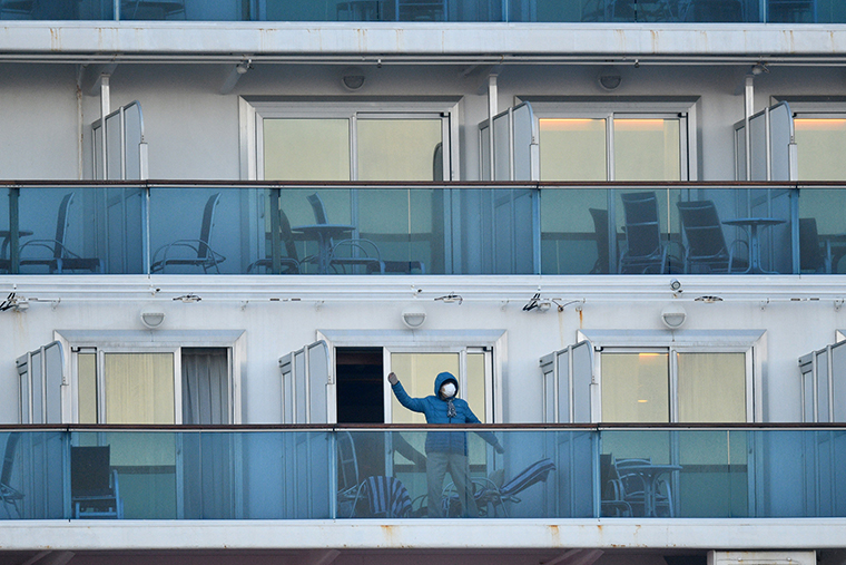 A passenger is seen on a balconies of the Diamond Princess cruise ship, with around 3,600 people quarantined onboard due to fears of the new coronavirus, at the Daikaku Pier Cruise Terminal in Yokohama port on February 13, 2020. - At least 218 people on board a cruise ship quarantined off Japan have tested positive for the novel COVID-19 coronavirus, authorities said February 13 as they announced plans to move some elderly passengers off the ship. (Photo by Kazuhiro NOGI / AFP) (Photo by KAZUHIRO NOGI/AFP via Getty Images)