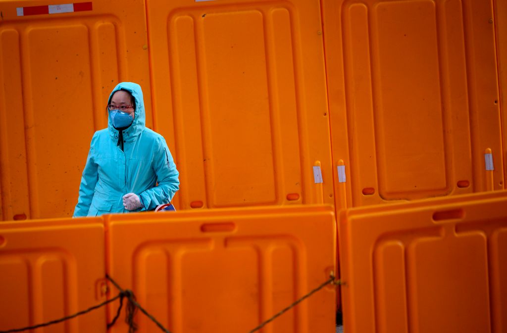 A woman wearing a protective facemask walks past construction barriers along a street in Shanghai on February 19, 2020. - The death toll from China's new coronavirus epidemic jumped past 2,000 on February 19 after 136 more people died, with the number of new cases falling for a second straight day, according to the National Health Commission. (Photo by NOEL CELIS / AFP) (Photo by NOEL CELIS/AFP via Getty Images)