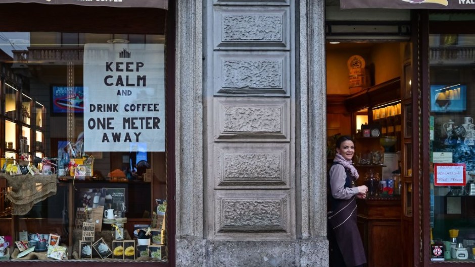 TOPSHOT - A waitress looks on by a sign advising clients to keep distance on a cafe's window on March 10, 2020 in downtown Milan. - Italy imposed unprecedented national restrictions on its 60 million people on March 10, 2020 to control the deadly coronavirus, as China signalled major progress in its own battle against the global epidemic. (Photo by MIGUEL MEDINA / AFP) (Photo by MIGUEL MEDINA/AFP via Getty Images)