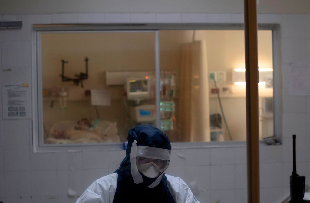 A doctor remains in an observation cabin in front of a patient infected with the novel coronavirus COVID-19, in the intensive care unit of the San Rafael Hospital in Santa Tecla, La Libertad, just 10 km from the Salvadorean capital San Salvador, on May 16, 2020. - The San Rafael Hospital, which has been assigned to care for 100 COVID-19 patients whose cases range from "severe to critical," is leading in their recovery, and part of the success, according to hospital director Yeerles Luis Ramirez, has been early treatment. (Photo by Yuri CORTEZ / AFP) (Photo by YURI CORTEZ/AFP via Getty Images)