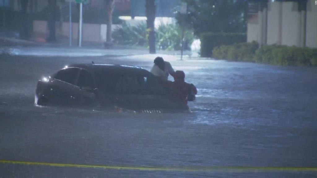 El momento en que un periodista rescata a una mujer de un auto inundado